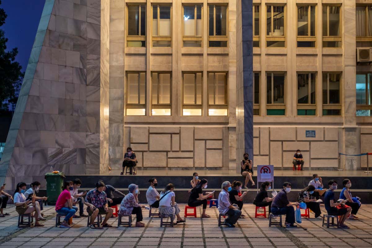 HANOI, VIETNAM - SEPTEMBER 10: People wait in a queue to receive their first dose of the AstraZeneca vaccine at a public COVID-19 vaccination centre on September 10, 2021 in Hanoi, Vietnam. Hanoi is aiming to mass test the entire city and vaccinate all its adult population with at least one Covid-19 vaccine shot by September 15. Vaccinations in Vietnam are picking up pace as increased supplies arrive in the country, which is the EU's largest trading partner in Southeast Asia. (Photo by Linh Pham/Getty Images)