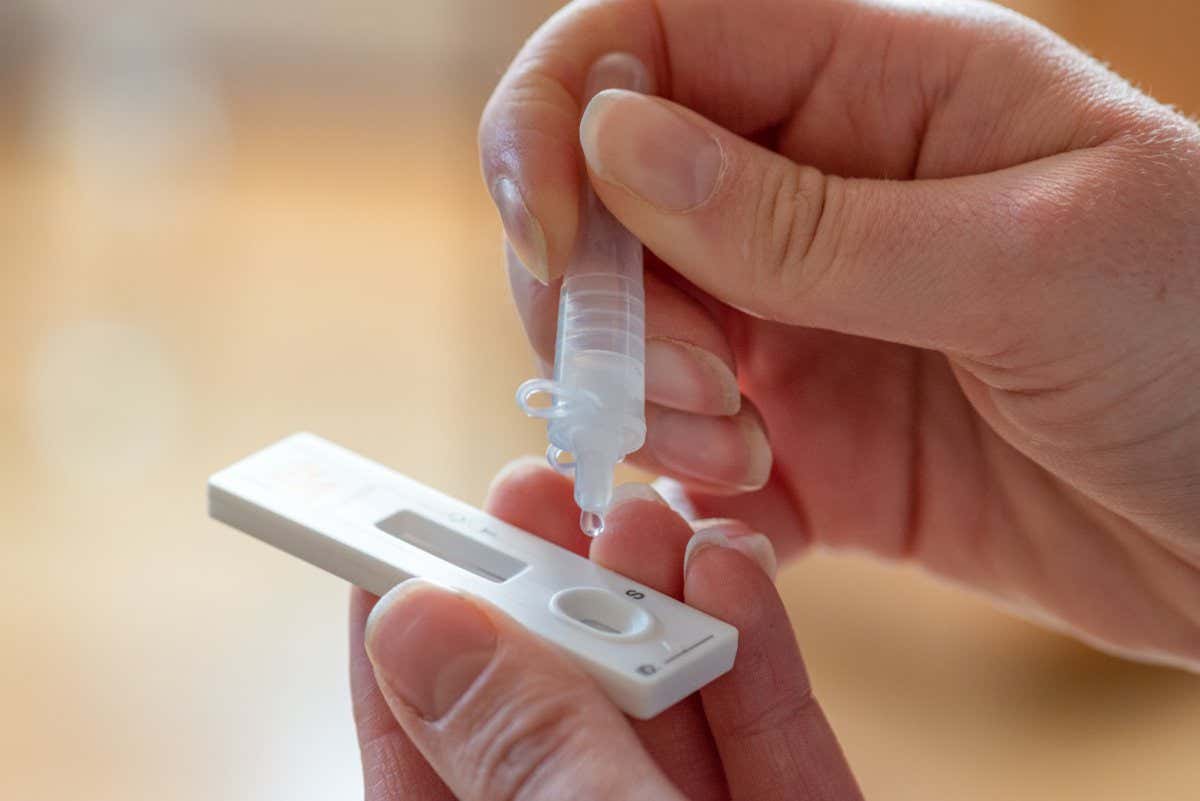 A person drops solution onto a lateral flow test for covid-19