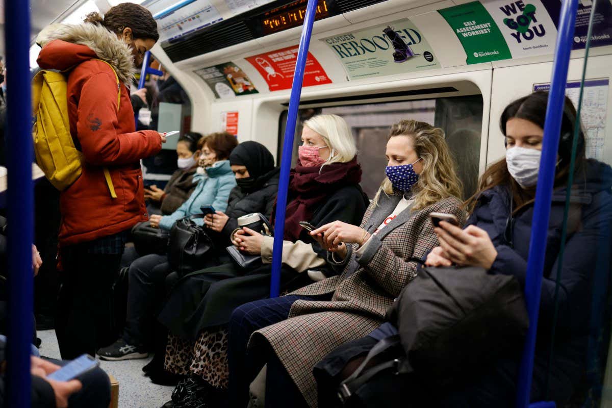 Commuters, some wearing face masks, on a London underground train