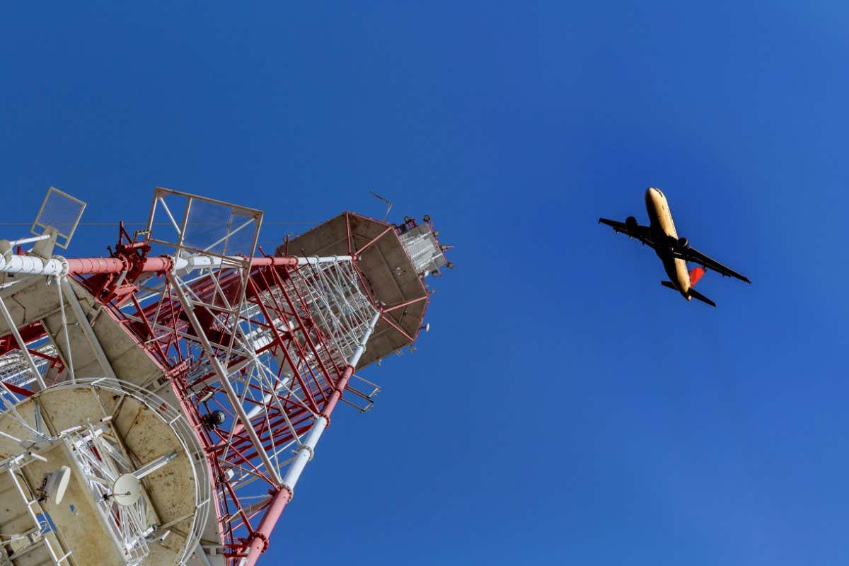 TV tower and plane Telecommunications tower against blue sky, in red and white