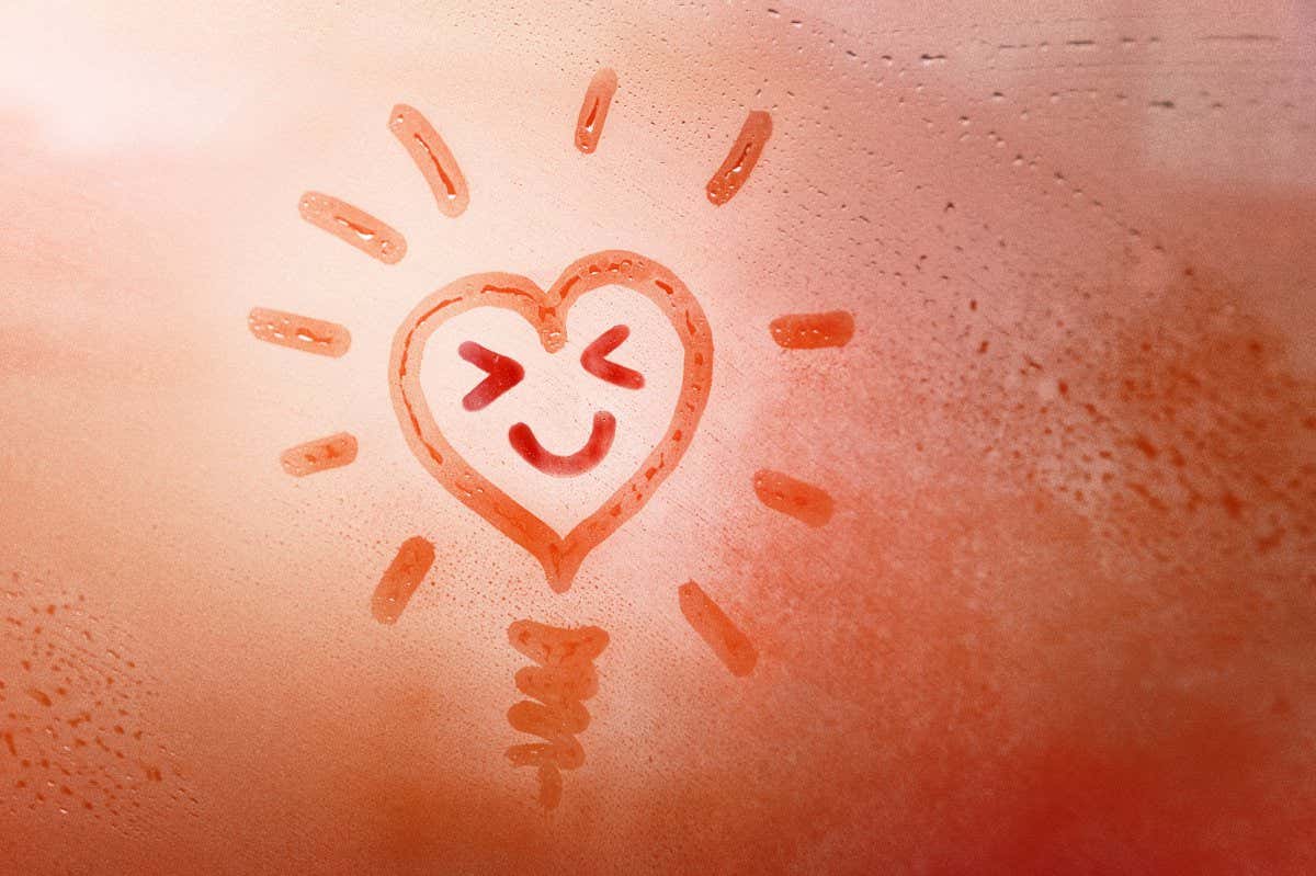 speech buble heart like sun and lamp with happy smile face with eyes narrowed on foggy window spattered with drops city, yellow red color, copyspace