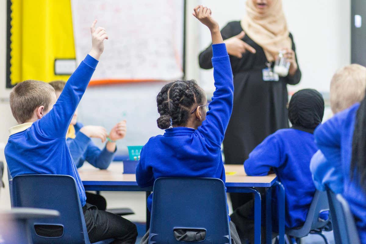 Pupils raise hands at a primary school in England