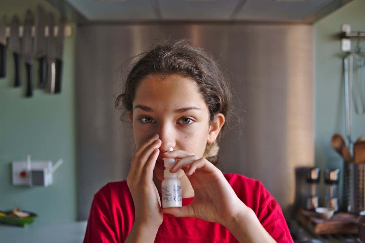 2BWWJP8 Child hay fever sufferer using nasal spray treatment for some relief from the symptoms of the allergy.