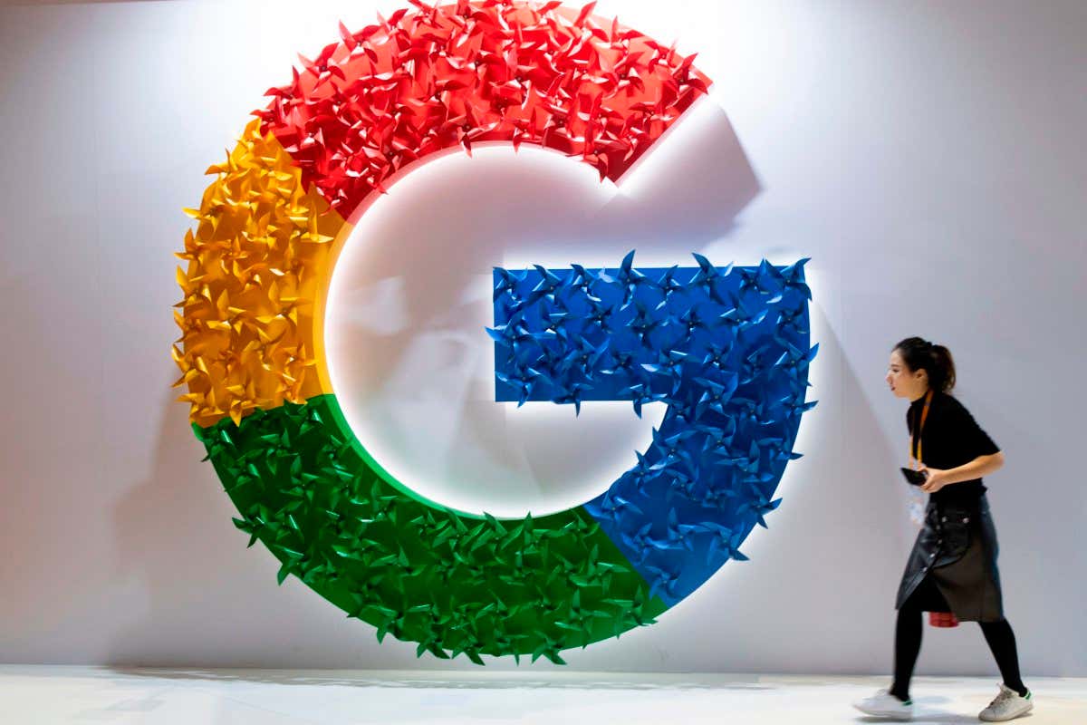 TOPSHOT - This picture taken on November 5, 2018 shows a woman passing a booth of Google at the first China International Import Expo (CIIE) in Shanghai on . (Photo by Johannes EISELE / AFP) (Photo credit should read JOHANNES EISELE/AFP via Getty Images)