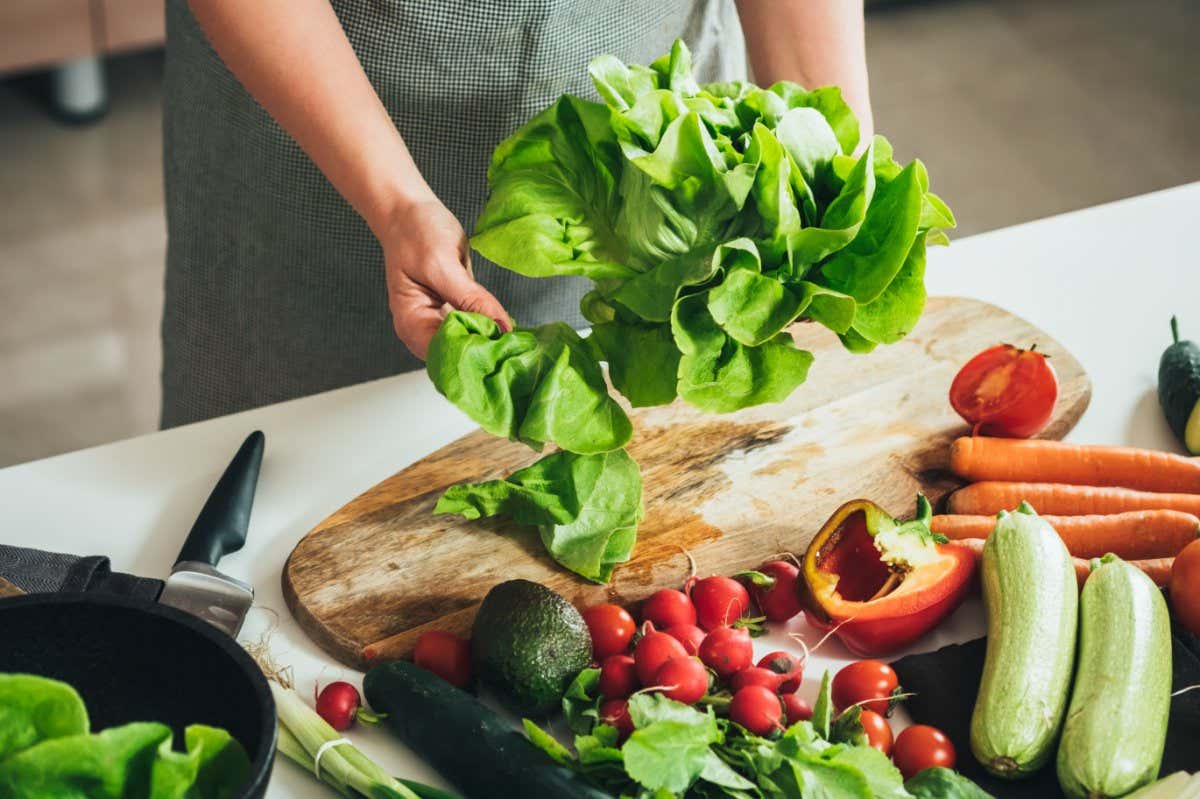 Close Up Photo of Woman Hands Making Fresh Salad on a Table Full with Organic Vegetables. An anonymous housewife making lunch with fresh colorful vegetables at kitchen table.; Shutterstock ID 2068275398; purchase_order: -; job: -; client: -; other: -