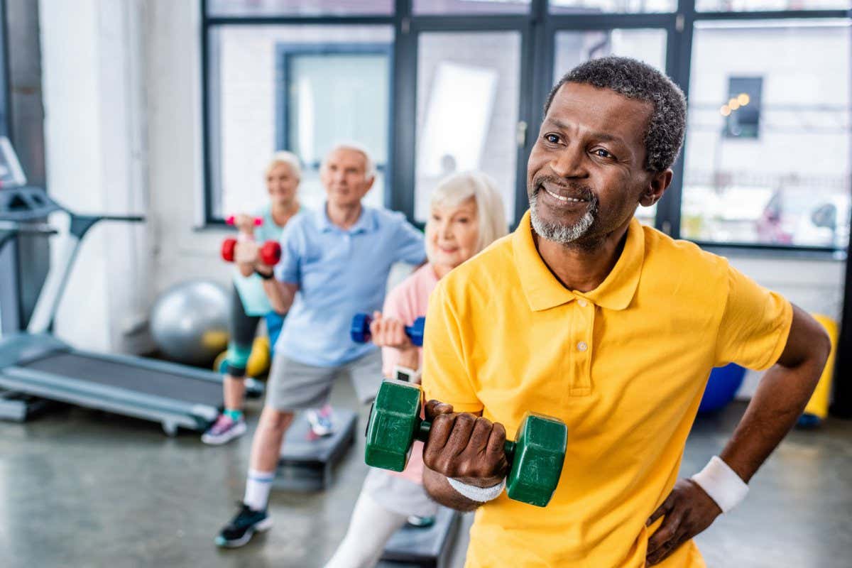 african american man and his friends synchronous exercising with dumbbells at sports hall; Shutterstock ID 1272152962; purchase_order: -; job: -; client: -; other: -