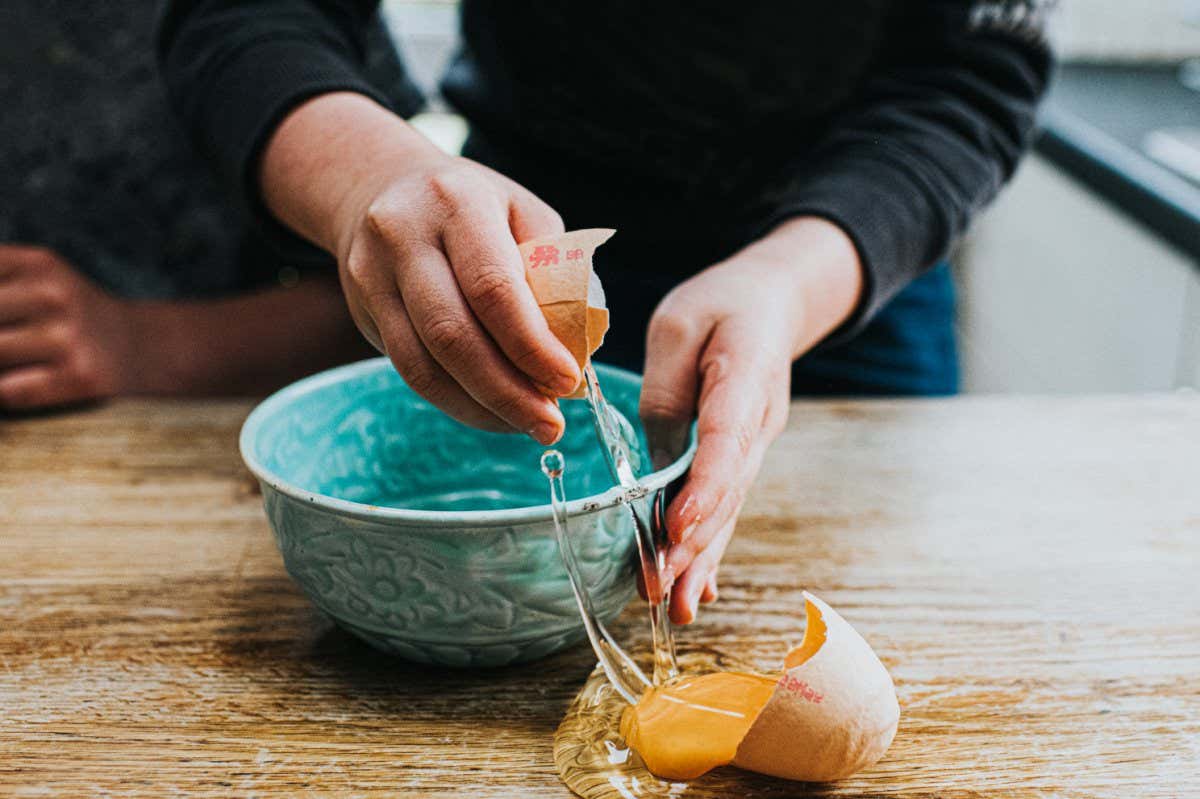 Child breaking an egg into a bowl, accidentally making a mess in the process. Space for copy.