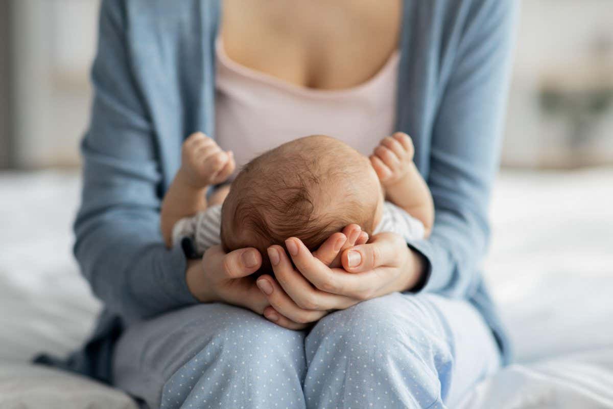 Mother Care. Unrecognizable mom holding newborn baby on her laps