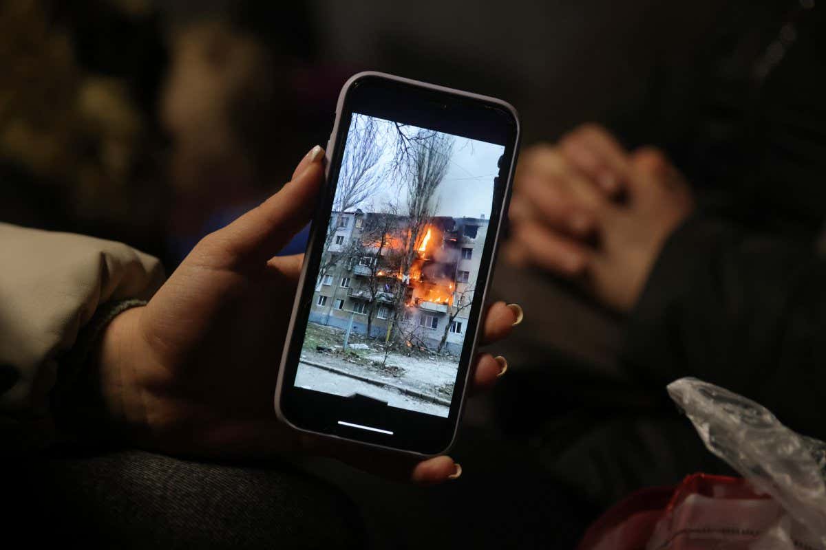 MEDYKA, POLAND - MARCH 09: Iryna Holoshchapova, a Ukrainian refugee who fled the embattled city of Mykolaiv, shows a video on her smartphone of a friend's apartment block in Mykolaiv on fire following a Russian attack as she, her son Tibor and mother Halina rest in a heated tent at the Medyka border crossing on March 09, 2022 in Medyka, Poland. Yulia said her friend was not in the building when it was struck. Over one million people have arrived in Poland from Ukraine since the Russian invasion of February 24, and while many are now living with relatives who live and work in Poland, others are journeying onward to other countries in Europe. (Photo by Sean Gallup/Getty Images)