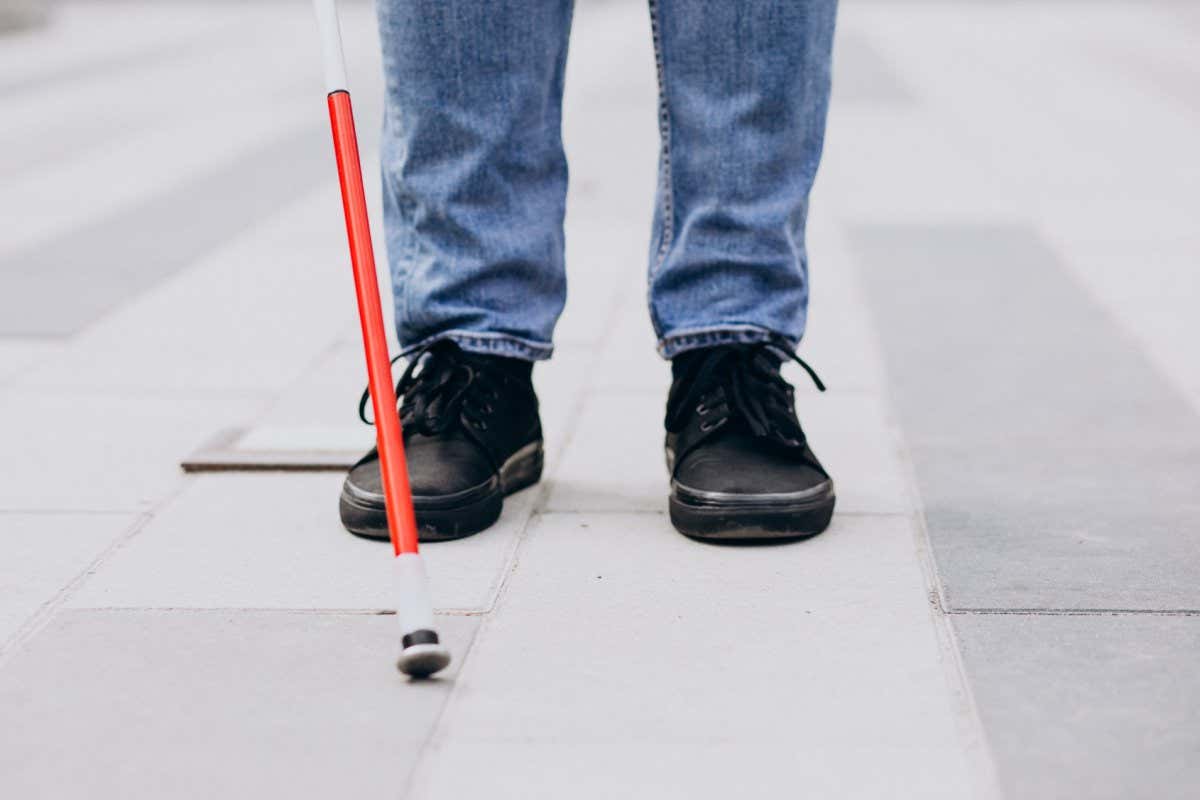 Stock image of a blind person walking with a stick