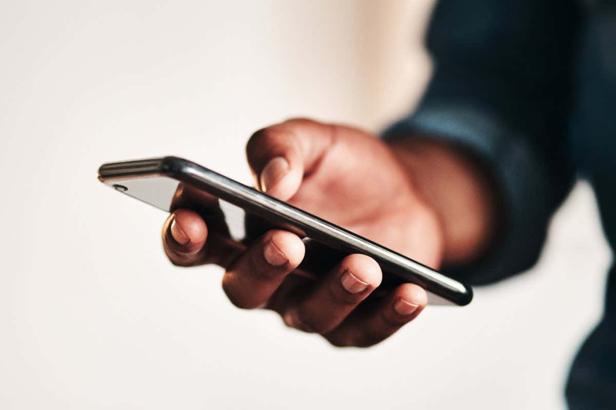 Cropped shot of an unrecognizable businessman standing alone in his home office and texting on his cellphone