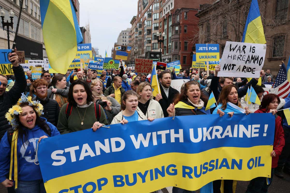 Boston - March 6: People hold a banner reading Stand with Ukraine! Stop buying Russian oil as they take part in a Peace March for Ukraine from Copley Square to Parkman Bandstand on the Boston Common in Boston on March 6, 2022. The protests marked the second straight Sunday people have marched through Boston, as Russias invasion of its neighbor entered its 11th day. (Photo by Jessica Rinaldi/The Boston Globe via Getty Images)