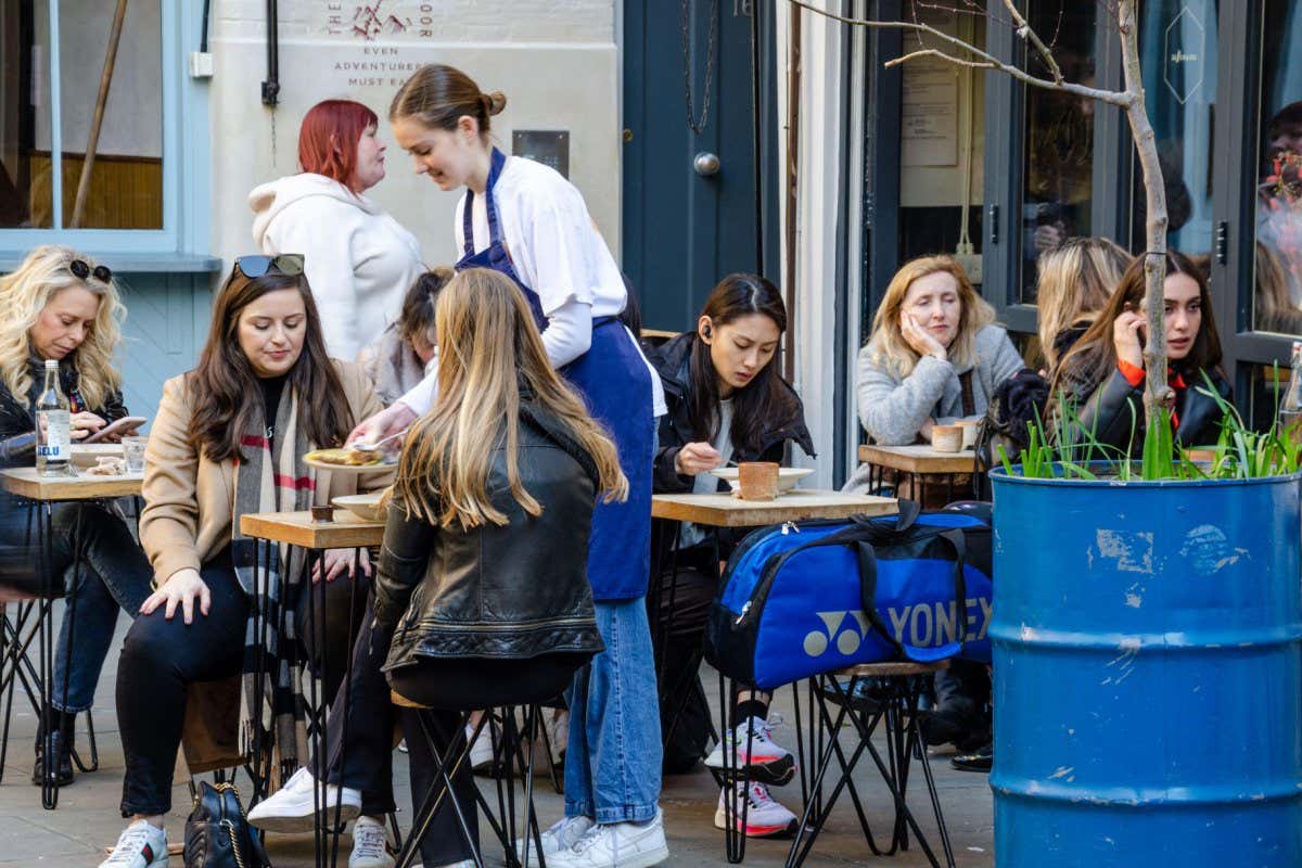 People eating outside at a cafe in Neal's Yard near Covent Garden, London, UK.