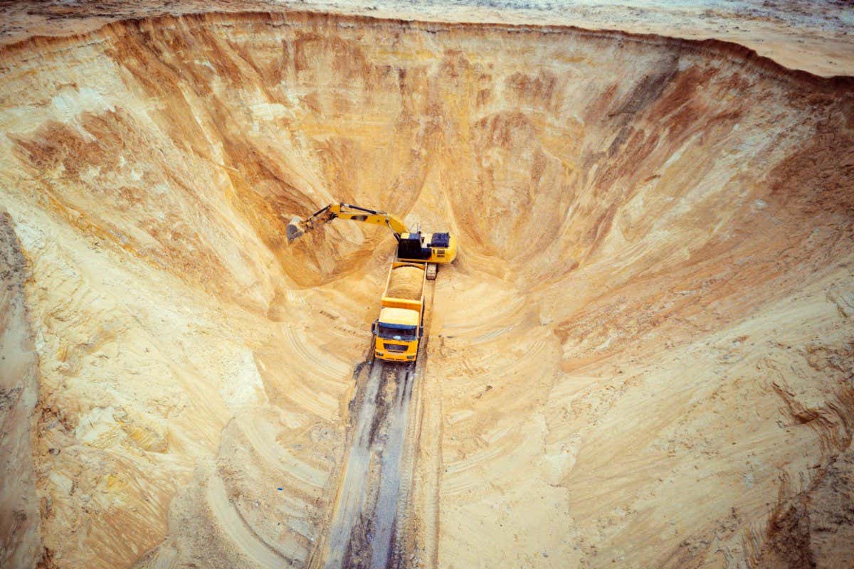 Excavator and dumper truck. Aerial view of loading sand into a truck. A heavy machinery - excavator and truck are working in the sand quarry.