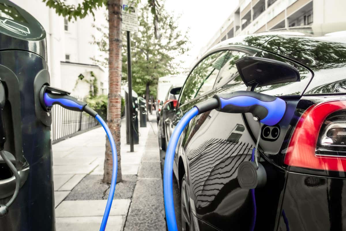 Electric car plugged in and changing on urban city street