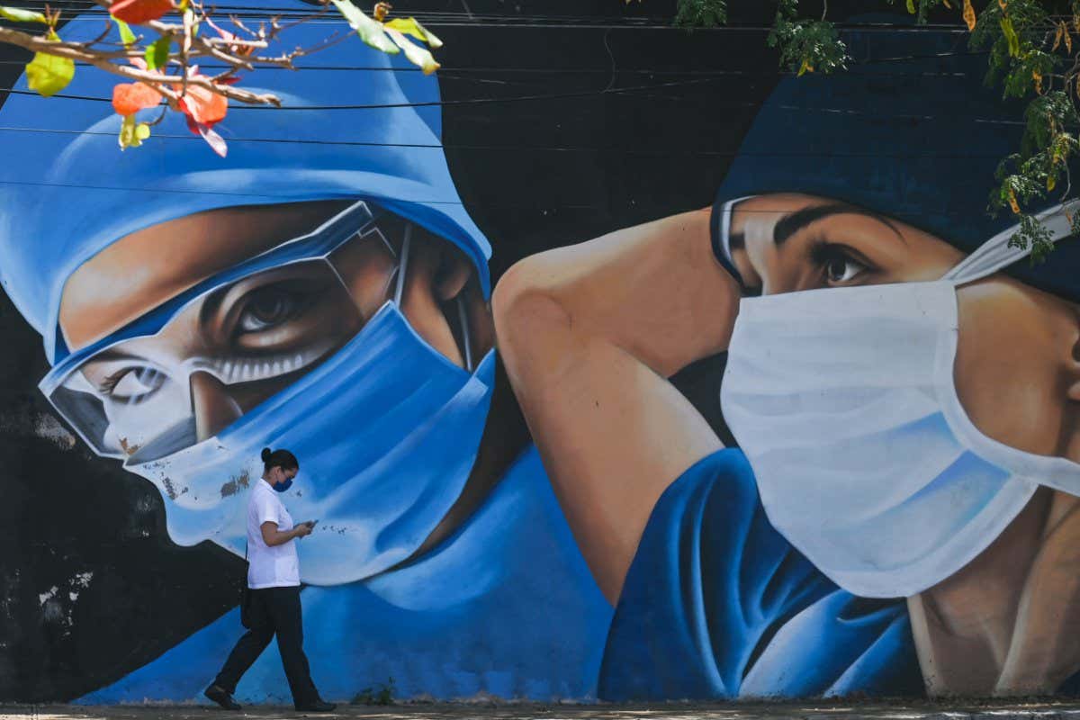A person walks past a mural of medical workers in Mérida, Mexico, in February