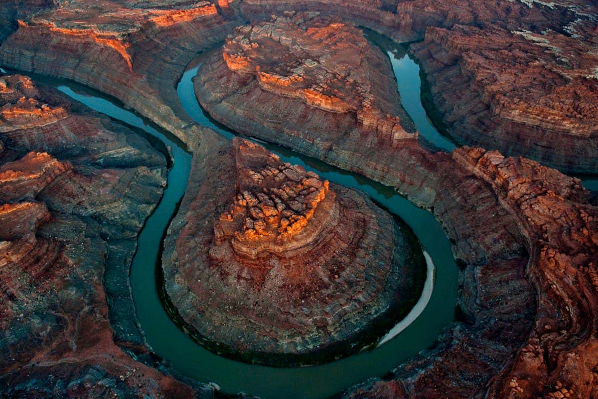 ???The Loop??? is located six miles above the Green River confluence in Canyonlands National Park, 50 miles downstream of Moab, Utah. The river follows an anticline atop 300-million-year-old salt beds buckling against the weight of more recent rock sediments. In 1964, President Johnson created Canyonlands National Park, as uranium prices fell and allowed him to work around numerous mining claims in the area.