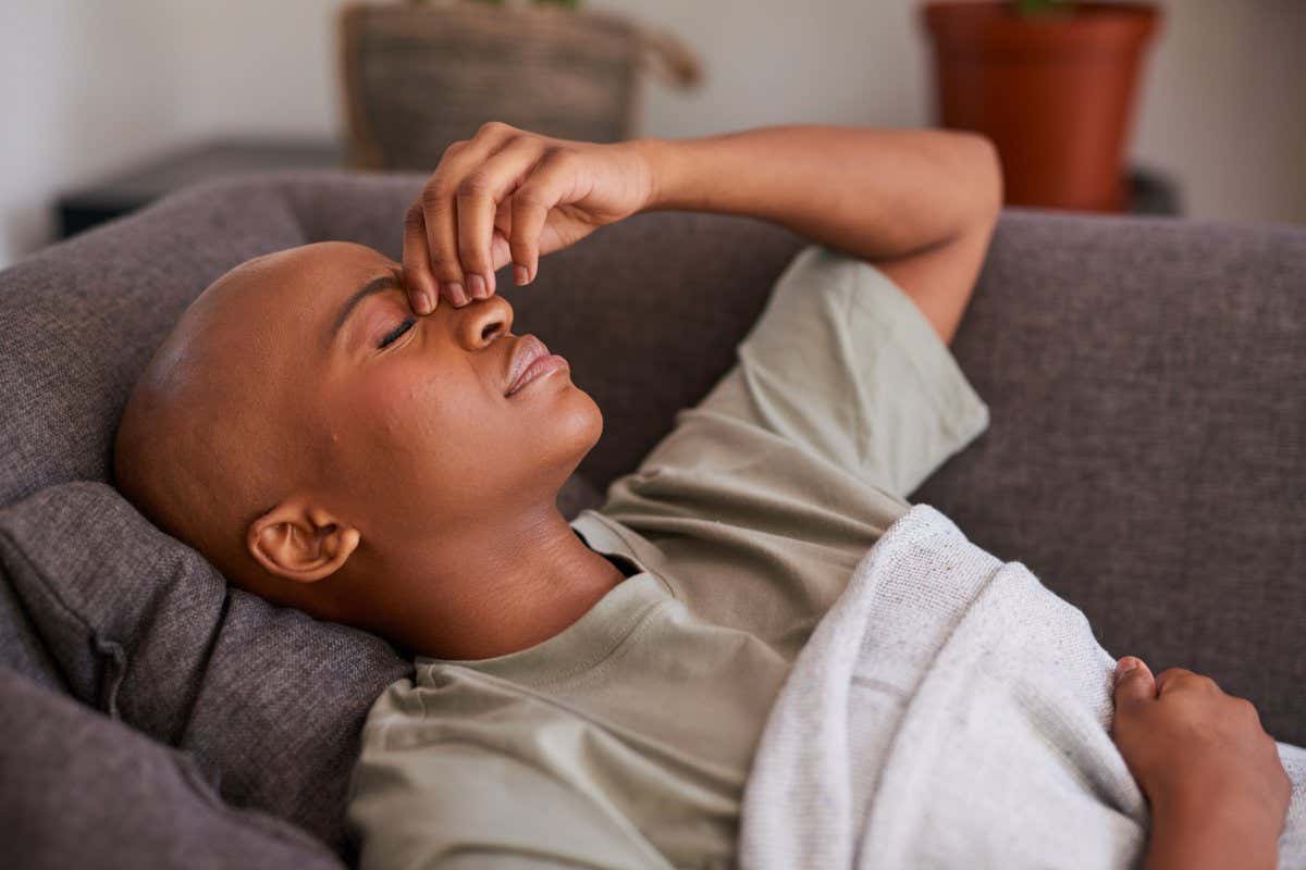 A stock image of an unwell person lying on a sofa