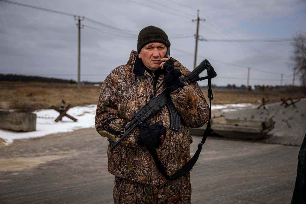 A member of the Ukrainian territorial defence units talks on their phone during observation of Russian troops movements around the village of Velyka Dymerka, 40km east of Kyiv, on 9 March
