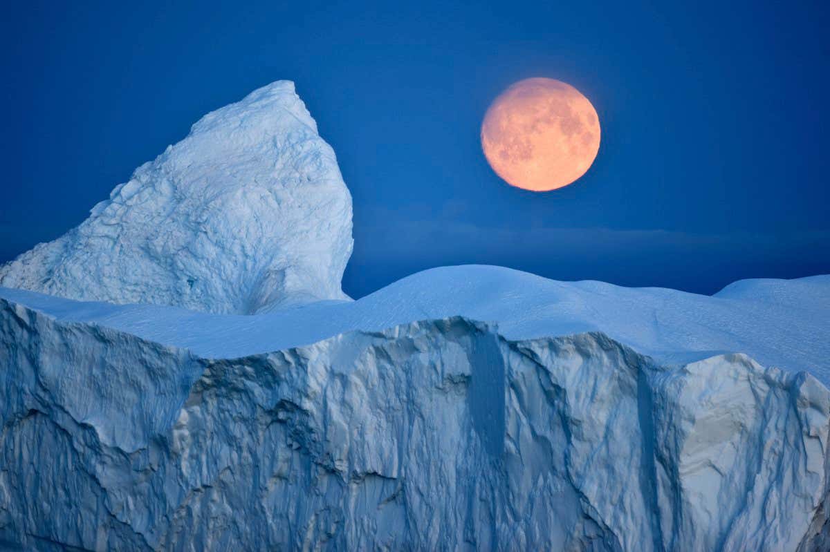 Full moon over an iceberg at dusk, Saqqaq, Disko Bay, Greenland, September 2009