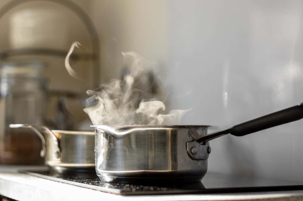 Blur background. Selective focus. Boiling water with steam in a pot on an electric stove in the kitchen; Shutterstock ID 1703285752; purchase_order: -; job: -; client: -; other: -