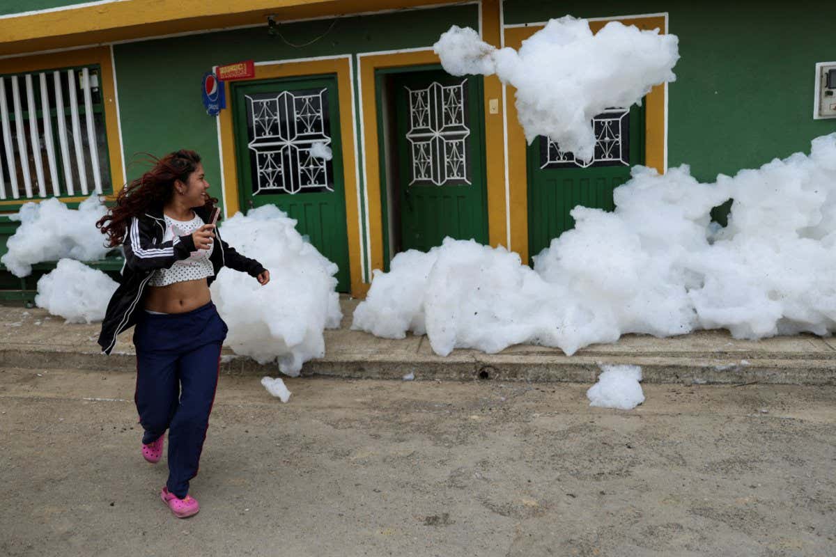 A woman flees from the polluting foam generated by a river full of waste, at the entrance of her house, in Mosquera, Colombia April 27, 2022. REUTERS/Luisa Gonzalez TPX IMAGES OF THE DAY - RC2RVT90Q4JF