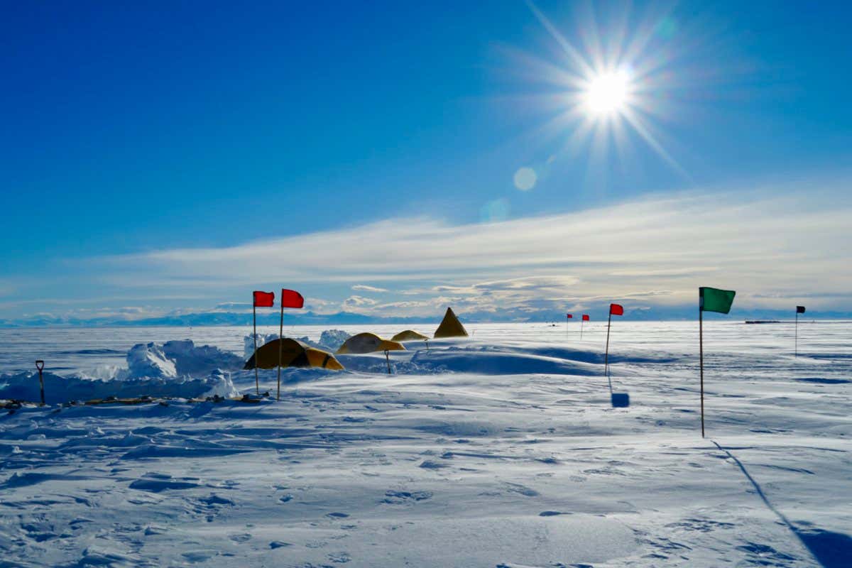 View of the four-person team?s field camp on the Whillans Ice Stream, West Antarctica with the Transantarctic Mountains in the background.