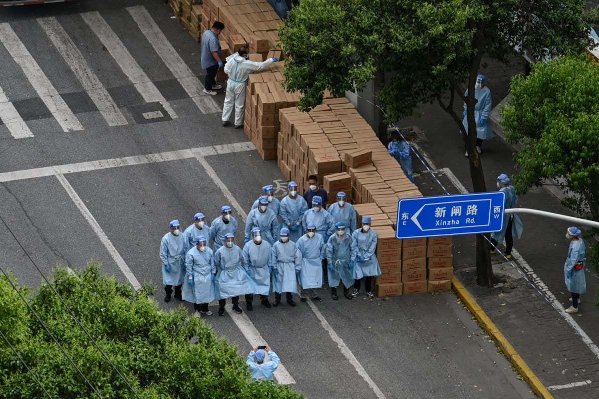 Workers in personal protective equipment deliver food during the ongoing covid-19 lockdown in the Jing'an district of Shanghai in China on 7 May 2022