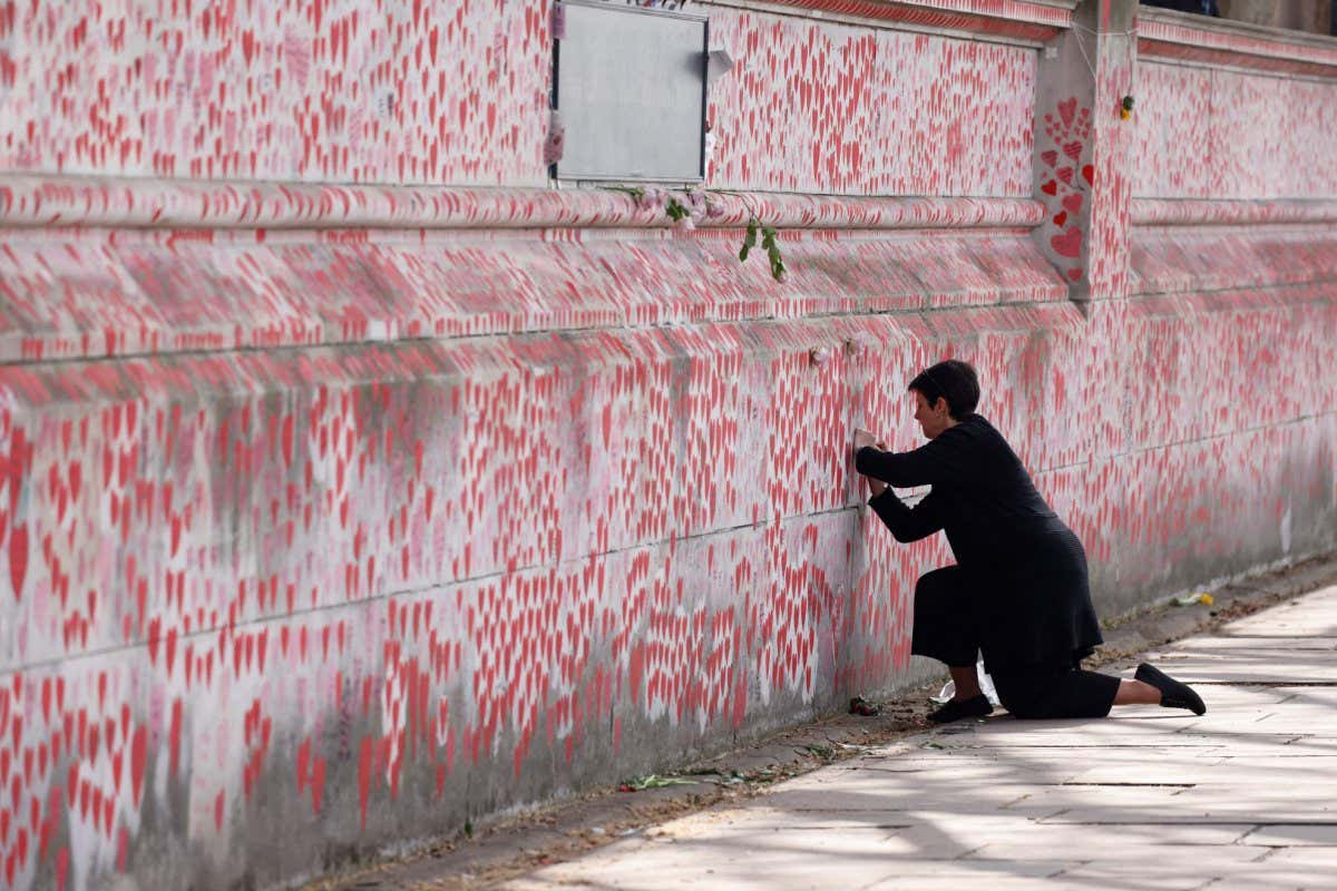 A person writes a message on the national covid-19 memorial wall in London, England
