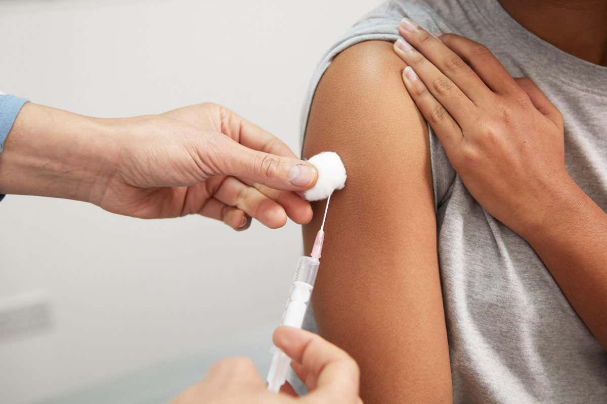 2HH66KH Doctor injecting COVID-19 vaccine through syringe in patient's arm at hospital