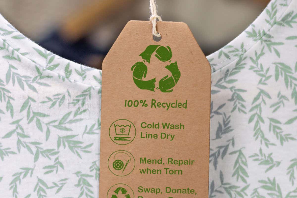 2F5J2D9 Recycled care label on t shirt, sustainable fashion wash cold, line dry, mend and repair, reuse, swap or donate with icons.