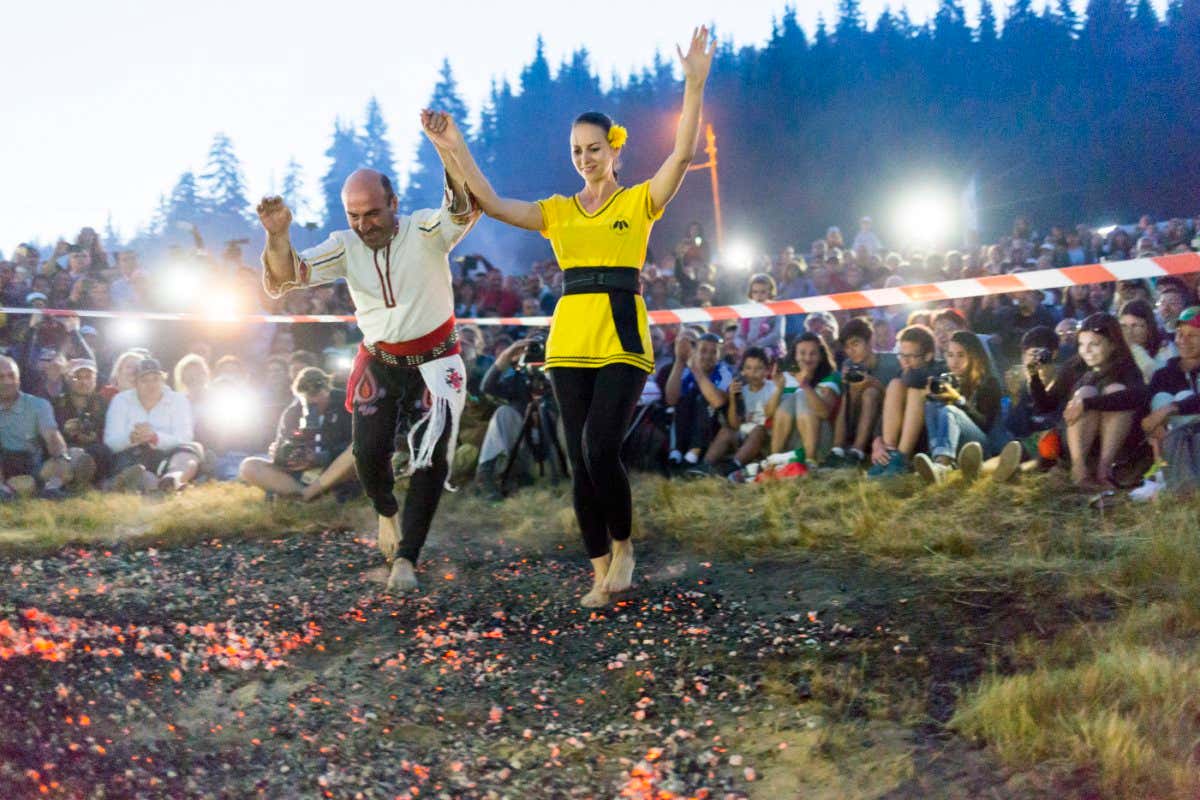 Rozhen, Bulgaria - July 18, 2015: A nestinar man and woman are walking on fire during a nestinarstvo show. The fire ritual involves a barefoot dance on smouldering embers performed by nestinari.