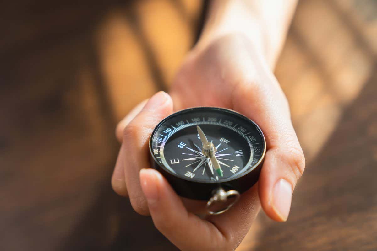 Close up of hand holding compass business navigate, passing through the crisis and growth in the economic.; Shutterstock ID 2115345185; purchase_order: -; job: -; client: -; other: -