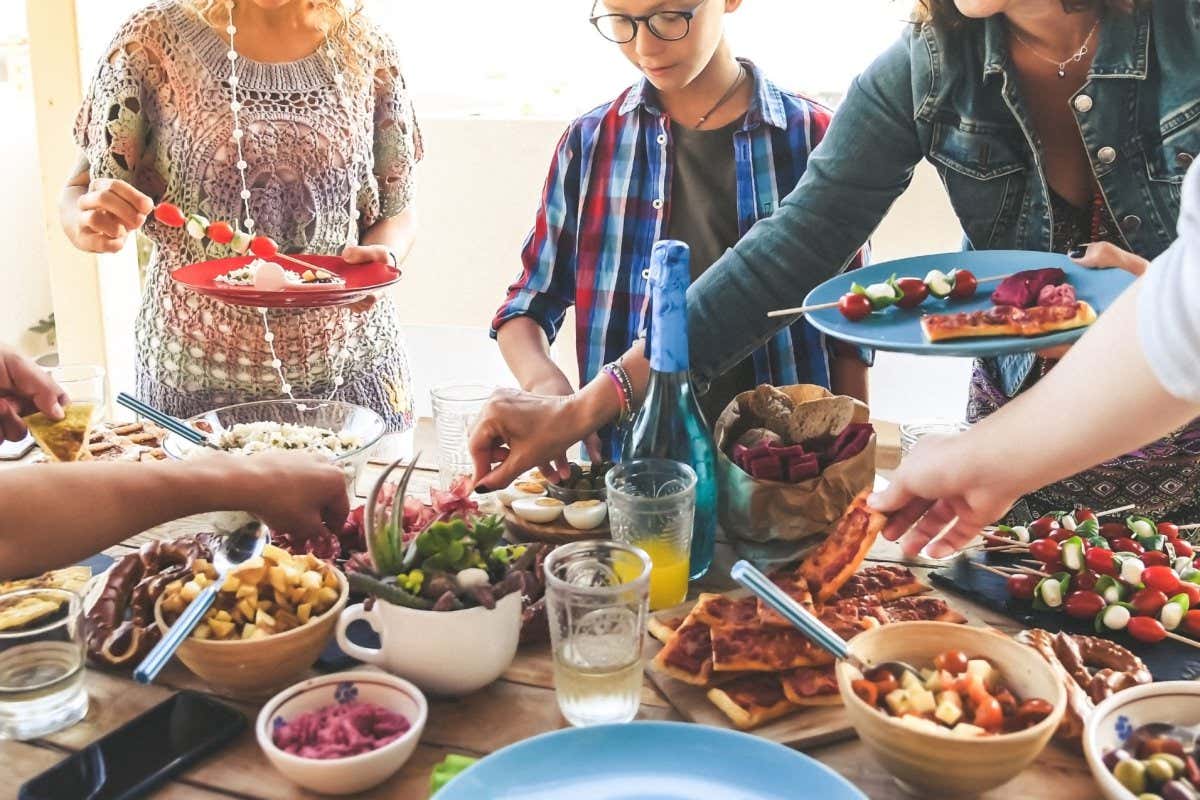 Summer aperitif with group of friends Joy and festivities in family Eavening with friend dinner on the terrace enjoying together. View from above of a table with many foods Happy hands taking viands; Shutterstock ID 1431755720; purchase_order: -; job: -; client: -; other: -