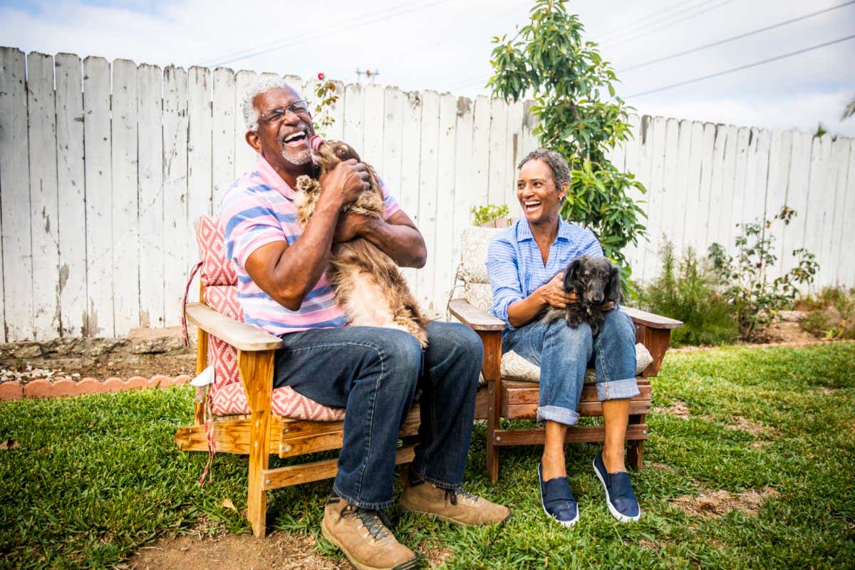 A senior black couple playing outdoors with their two dachshunds