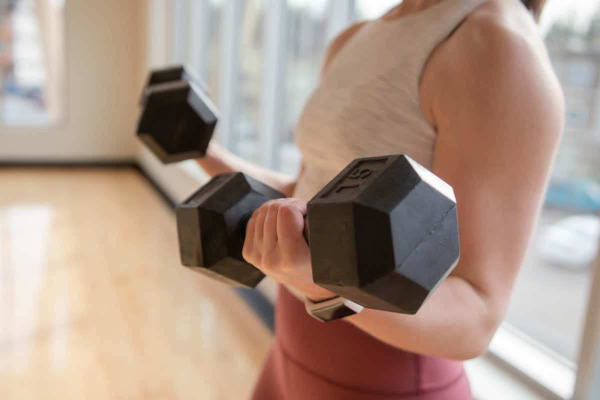 A woman lifting two 15-pound dumbbells.