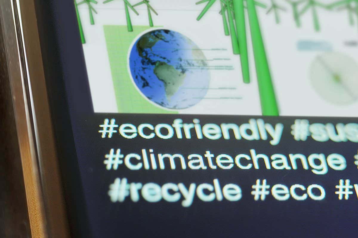 Close up image of a smart phone displaying conservation & ecological hashtags being spelt out, climate change; eco friendly etc