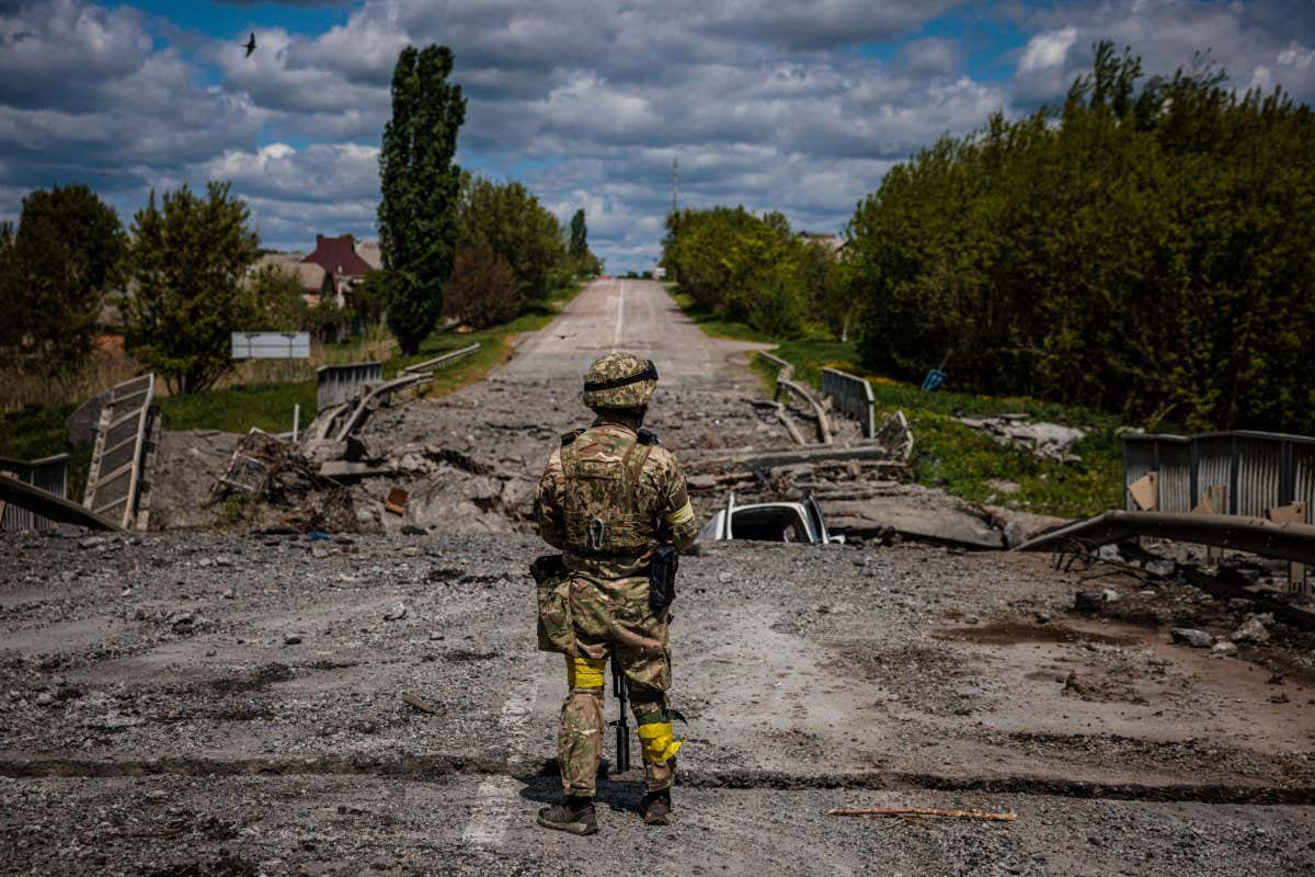 A Ukrainian soldier observing the area at a destroyed bridge