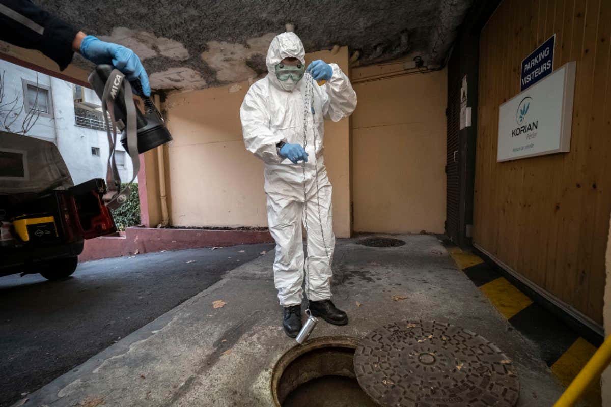 A person takes samples from Marseille sewage water near a retirement home in France to detect covid-19 traces in December 2020