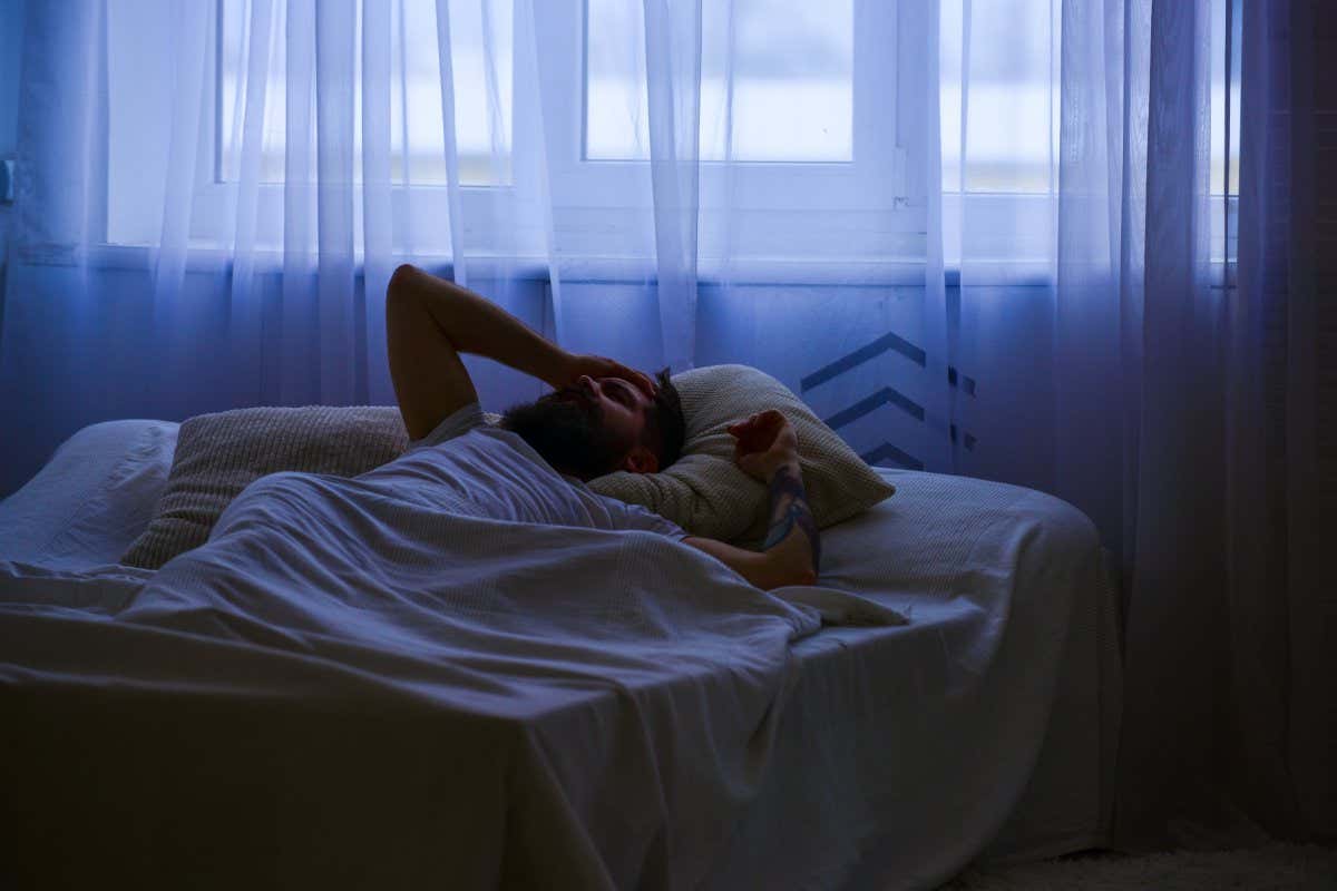 Man in shirt laying on bed awake