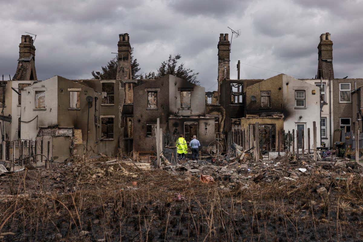 Damage is surveyed at homes gutted by fire on 25 July 2022 in Wennington, Greater London, the UK