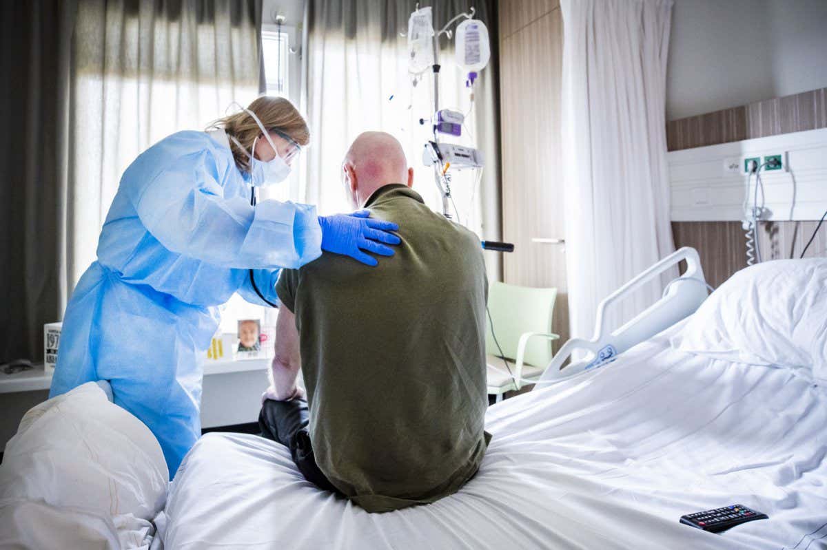 TOPSHOT - An attending physician listens to the breathing of a patient who is recovering after admission to an intensive care unit (ICU) in the coronavirus (COVID-19) patient nursing department of The HMC Westeinde Hospital in The Hague on April 4, 2020. (Photo by Remko DE WAAL / ANP / AFP) / Netherlands OUT (Photo by REMKO DE WAAL/ANP/AFP via Getty Images)