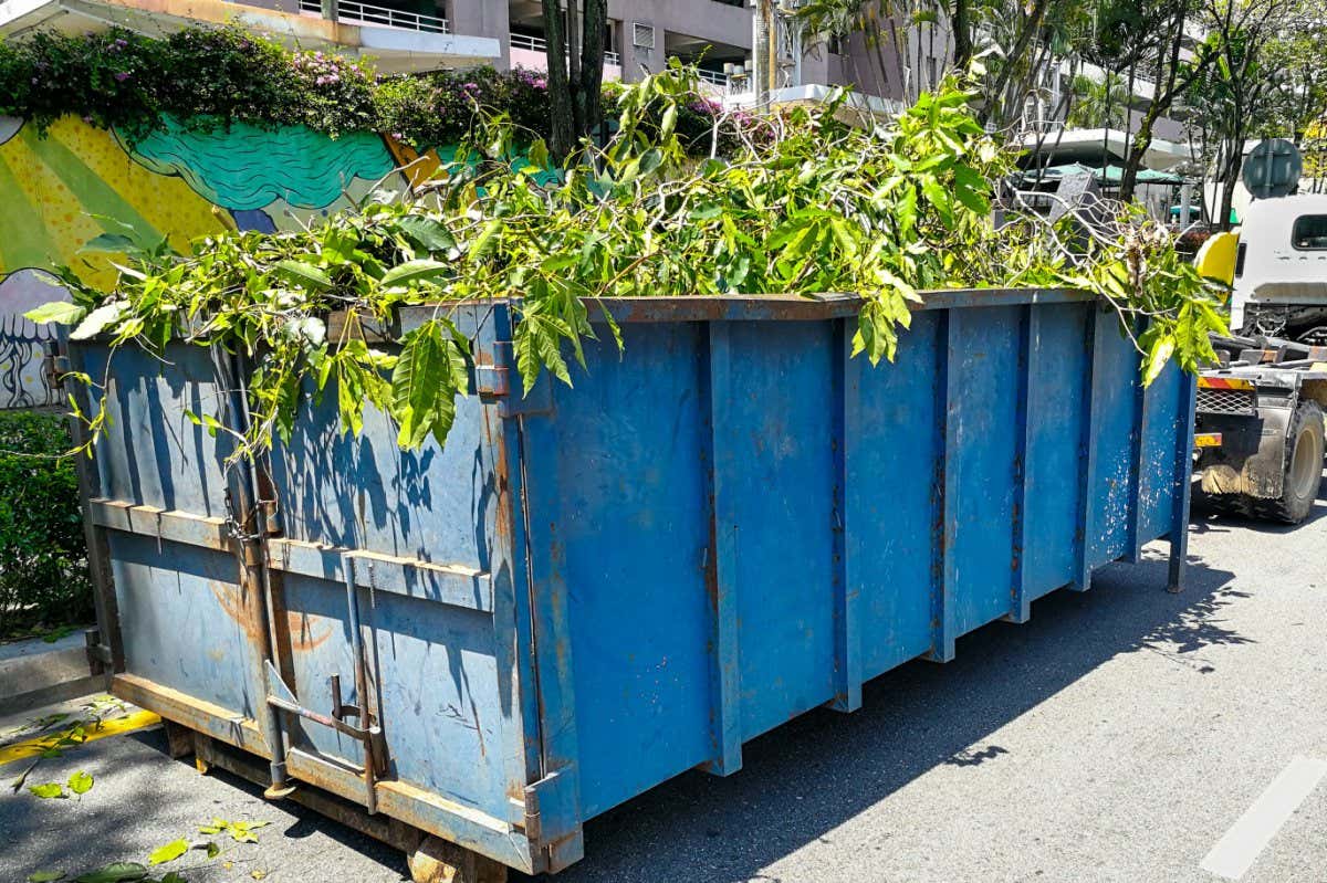 Garbage container bin latch with truck full of garden refuse, woods, chopped trees for disposal; Shutterstock ID 652230046; purchase_order: -; job: -; client: -; other: -