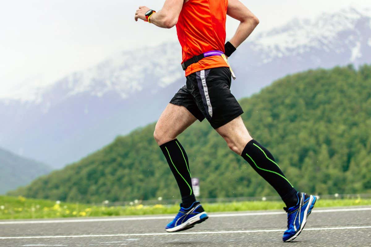 Runner in compression socks running on road in mountains