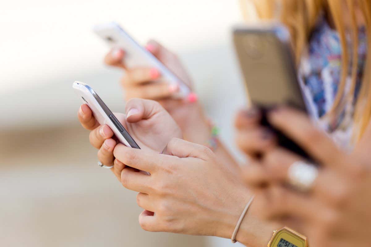 Portrait of three girls chatting with their smartphones at the park