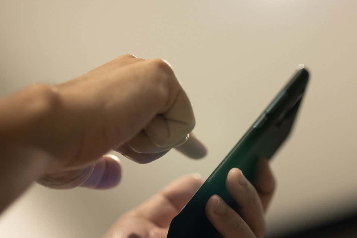 Close up hand use mobile app to control light in house.