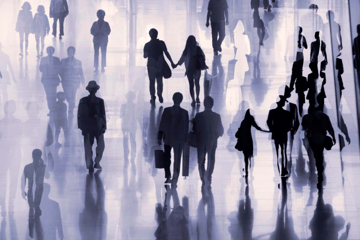 Large group of people on the move, some shopping, some holding hands, others just walking along.