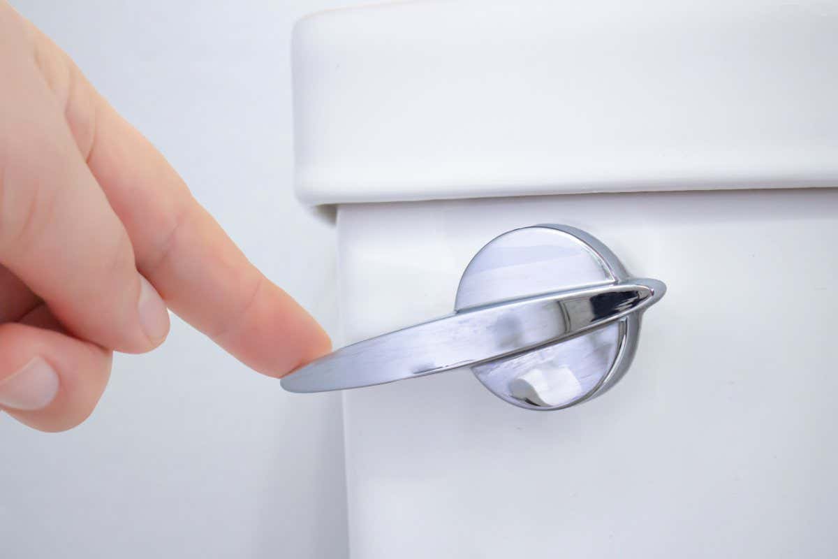 A person flushing a toilet on a washroom.; Shutterstock ID 1839502480; purchase_order: 170922 Culture; job: NS; client: NS; other:
