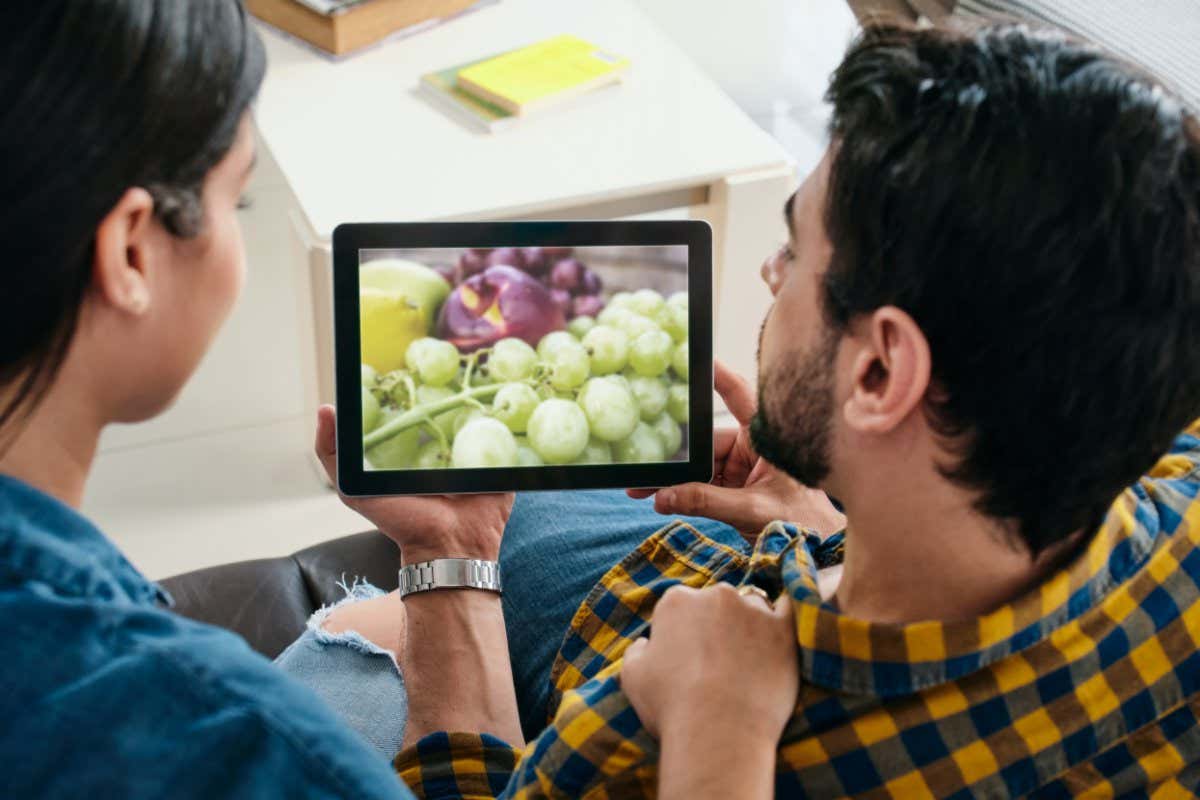People looking at a picture of grapes on a tablet