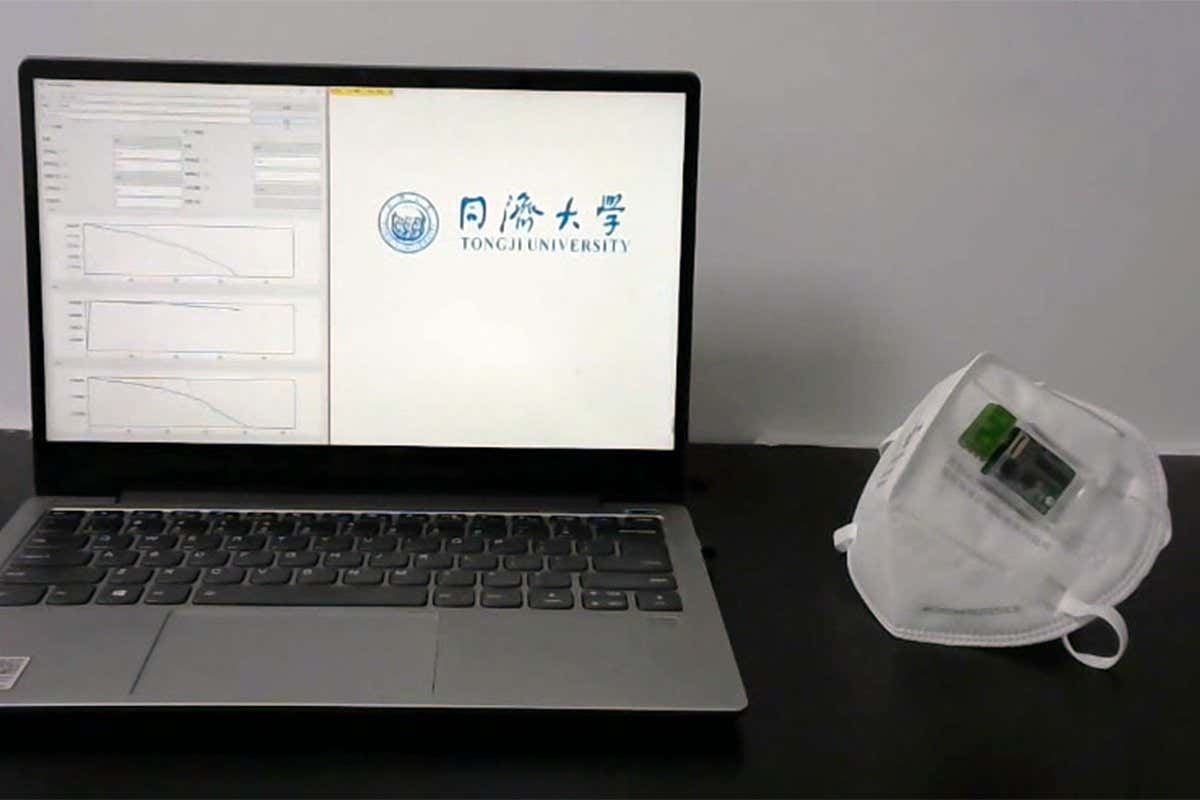 A face mask with virus sensor next to a laptop